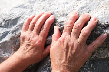 Close Up hands of senior woman on stone background. arthritis, osteoporosis, rheumatism concept.