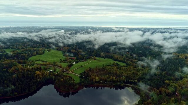 Aerial backwards shot showing idyllic landscape with clouds and tranquil lake at valley during sunlight