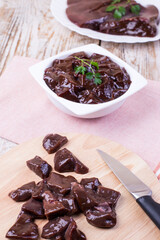 Raw liver on a white plate on a wooden background. Beef liver, top view. Offal in its raw form.