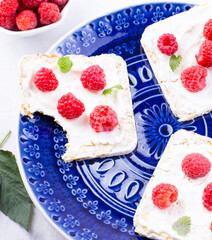 Toast with cream cheese and fresh raspberries on a blue plate. A delicious summer dish for breakfast.