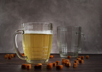 light beer in a glass mug with crackers on a dark background