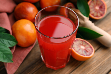 Tasty sicilian orange juice in glass, fruits and squeezer on wooden table