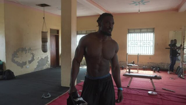 Black man shirtless walking in an old school gym. Cinematic slow-motion African man without t-shirt 4K.