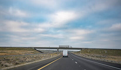 Fototapeta premium Commercial cargo mini van and big rig semi truck with semi trailer running at different directions for delivery loaded cargo