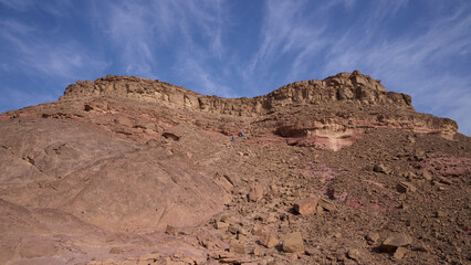 Fototapeta premium Hikers climbing mount Timna in Timna national park. Hiking path known as Israel National Trail passing through Timna national park. 