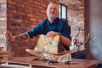 Tattooed grandfather butcher with knife and big steak