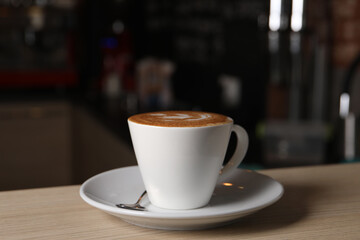 Cup of aromatic coffee on wooden table in cafe