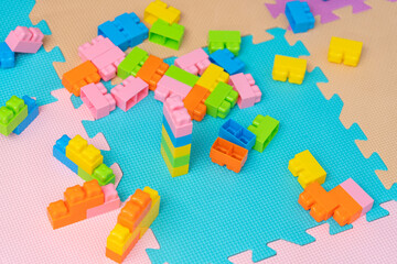 Colorful plastic construction bricks on the floor in the playroom. Soft floor made of foam material