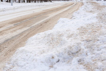 Winter road covered with snow and sprinkled with sand. Snow clearing and road maintenance by municipal services
