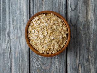 Gluten free wholegrain oat flakes in wooden bowl.