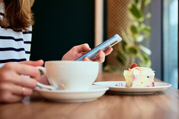 Woman hand use smartphone at cafe, surfing internet browser, have a coffee break. Online communication and social media