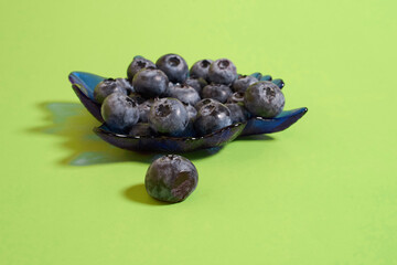 Ripe and rotten blueberries in a glass plate on a colored background