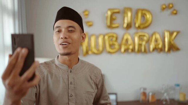 muslim male making a video call and taking selfie with eid mubarak decoration