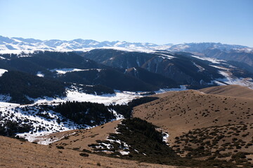Mountainous area near Almaty. Hills with vegetation and snow.