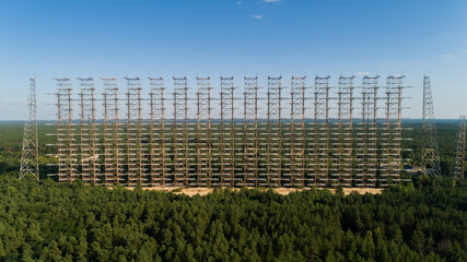 Fototapeta na wymiar Aerial view of the DUGA radar station near the city of Chernobyl-2 among the forest in sunny day. Drone shot Chernobyl exclusion zone in summer. Radiation