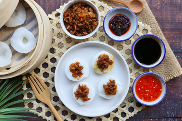 Steamed rice cake top with preserved turnip served with sweet soy sauce and chili sauce - In Chinese food called Chwee Kueh at top view on wood table
