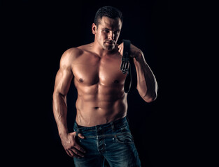 Fototapeta na wymiar Handsome muscular man posing. Guy in jeans with perfect abdominal muscles.