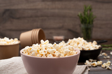 Bowl with popped corns on kitchen table with rosemary on background