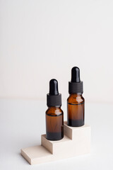 Amber glass bottles with dropper pipette with serum or essential oil on concrete plate for product presentation. Skin care cosmetic. Beauty concept for face body care