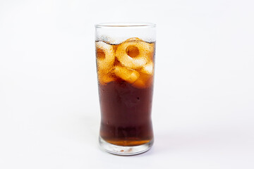 Coca-Cola flavored black soft drink with ice in a clear glass on a white background.