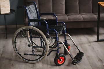 Fototapeta na wymiar Empty wheelchair in black with large wheels and manual controls on home background. Barrier-free area. Nobody. Apartment room. House. Medical equipment rental. Copy space. Disabled mobility. Banner.
