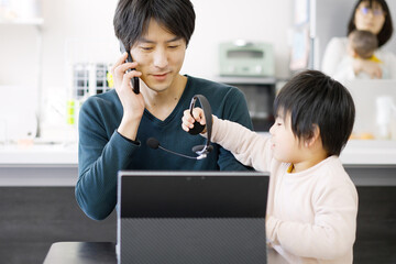 子供にテレワークの邪魔をされるアジア人男性