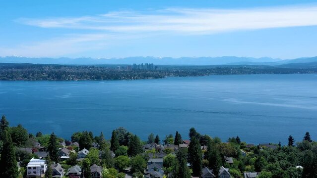 Drone flying over the Madrona Neighborhood with views of Lake Washington, snow covered Cascade Mountains, Bellevue and the neighborhood