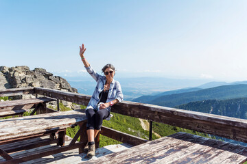 Hiker Woman Sitting and Waving in Rila Mountain with Stunning View. Musala Peak in Bulgaria in the Summer