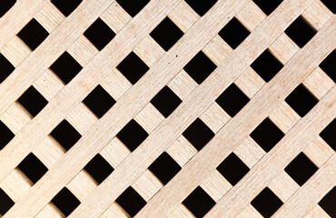 Latticed wooden deck of a yacht with diamond-shaped holes, close-up.