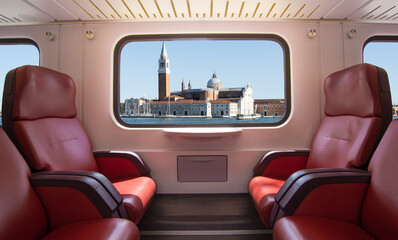 Train window with Venice landscape and empty seats.