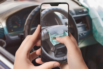 The girl takes a picture of the airbag on the steering wheel of the car at the scene of the accident on a smartphone to receive insurance compensation. Selective focus.
