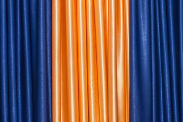 Draped fabric in golden orange and blue. background image.