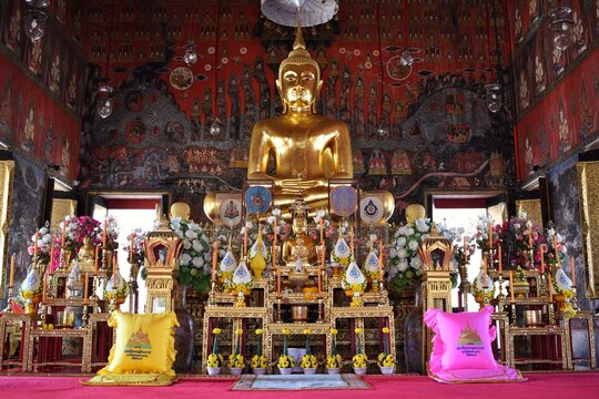 Golden Meditating Buddha Statue in the chapel of Wat Saket. The back is a mural depicting the three worlds - heaven, humans and hell.