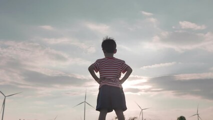 Asian boy child Play as a super hero or superman in The windmill farm field producing clean energy.