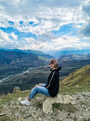 Naklejka na ściany i meble A girl on the background of a breathtaking view of the mountains in Dagestan, Caucasus. Russia 2021