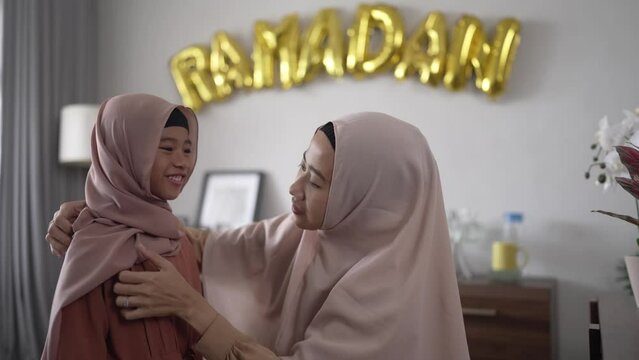 muslim mother fixing her dauhgter headscarf on ramadan