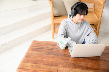 音楽を聴きながらパソコンで仕事をする女性　俯瞰