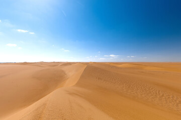Unique landscape of the Sahara Desert with the blue sky on the background.