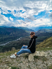 Naklejka premium A girl on the background of a breathtaking view of the mountains in Dagestan, Caucasus. Russia 2021