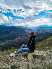 Naklejka premium A girl on the background of a breathtaking view of the mountains in Dagestan, Caucasus. Russia 2021