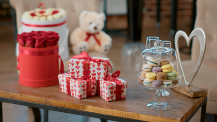 Empty living room with nobody in it having table with valentines-gift and red roses on it decorated by boyfriend to celebrate valentine day at home with girlfriend. Concept of romance anniversary