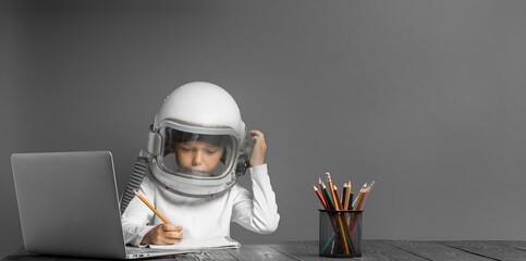 the child studies remotely at school, wearing an astronaut's helmet.