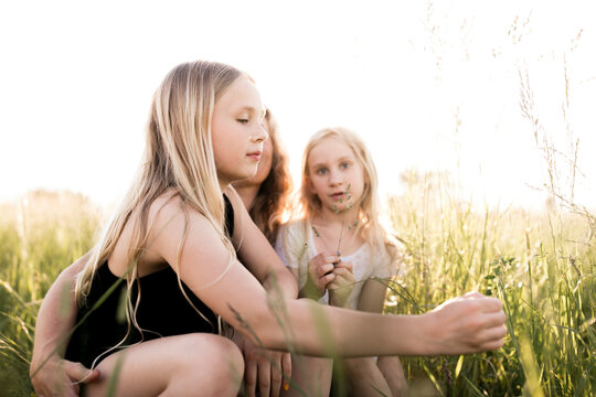 Sisters touching plants in field