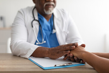 Close up of black male doctor holding female patient's hands