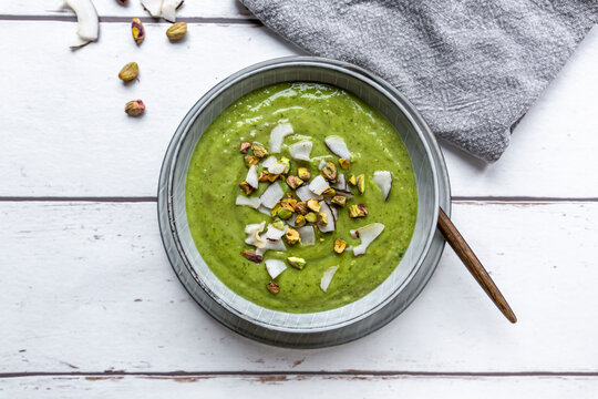 Studio shot of bowl of vegan pea soup with zucchini, broccoli, pistachios and coconut shreds