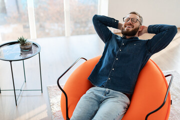 Happy Guy With Eyes Closed Relaxing Sitting In Chair Indoors