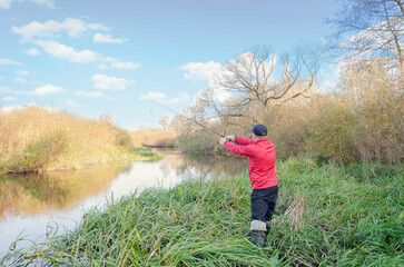 Angler athlete casts spinning rod into the river.