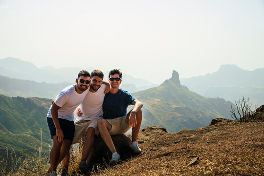 Happy young friends sitting on rock at Degollada de Becerra, Spain
