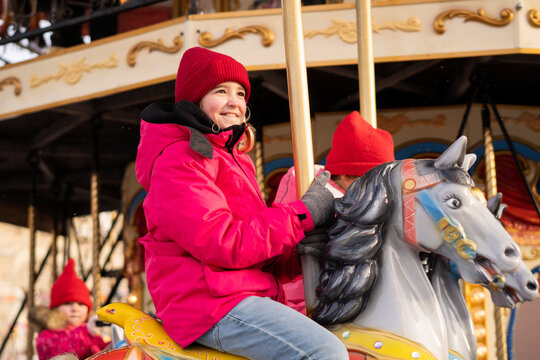 Smiling girl enjoying carousel ride at Christmas market