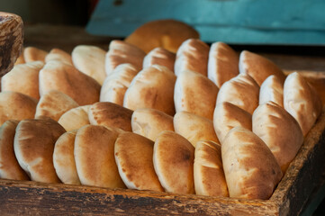 Freshly baked round pita or pocket bread neatly stacked in a wooden tray ready for delivery in the Machane Yehuda market in Jerusalem.